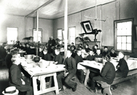 A room filled with tables and people sitting at them.