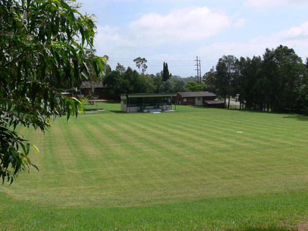 The oval at the Academy is a large area of green lawn with trees around the edge, and a few small buildings.