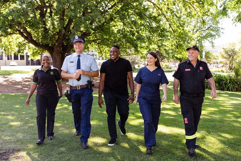 An image of four NSW government workers smiling and walking across the grass