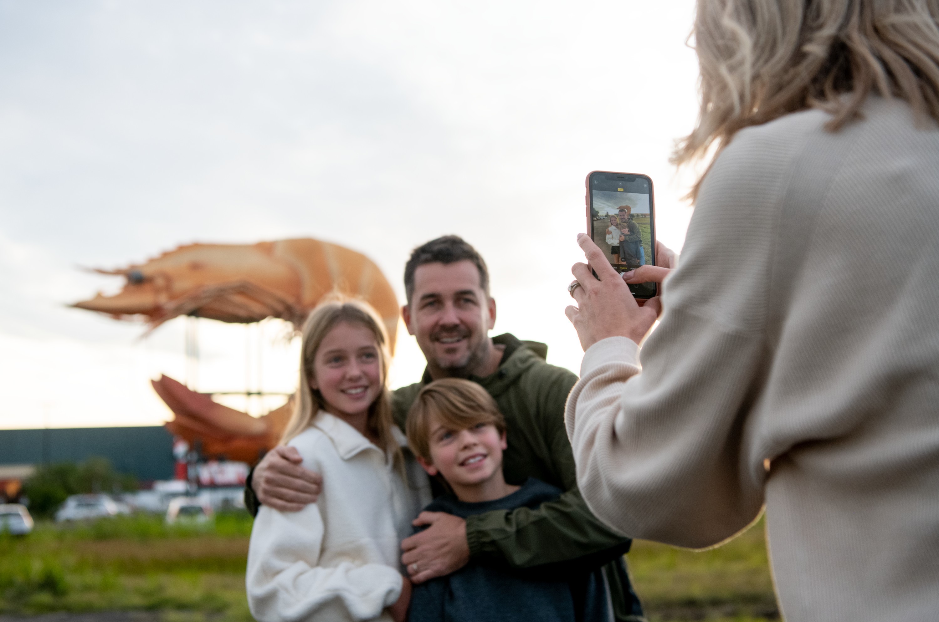 A photo of a family posing in front of the Big Prawn