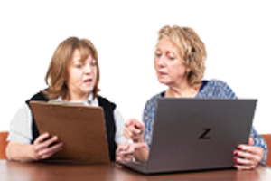 Image of tow females looking at a laptop and a pierce of paper
