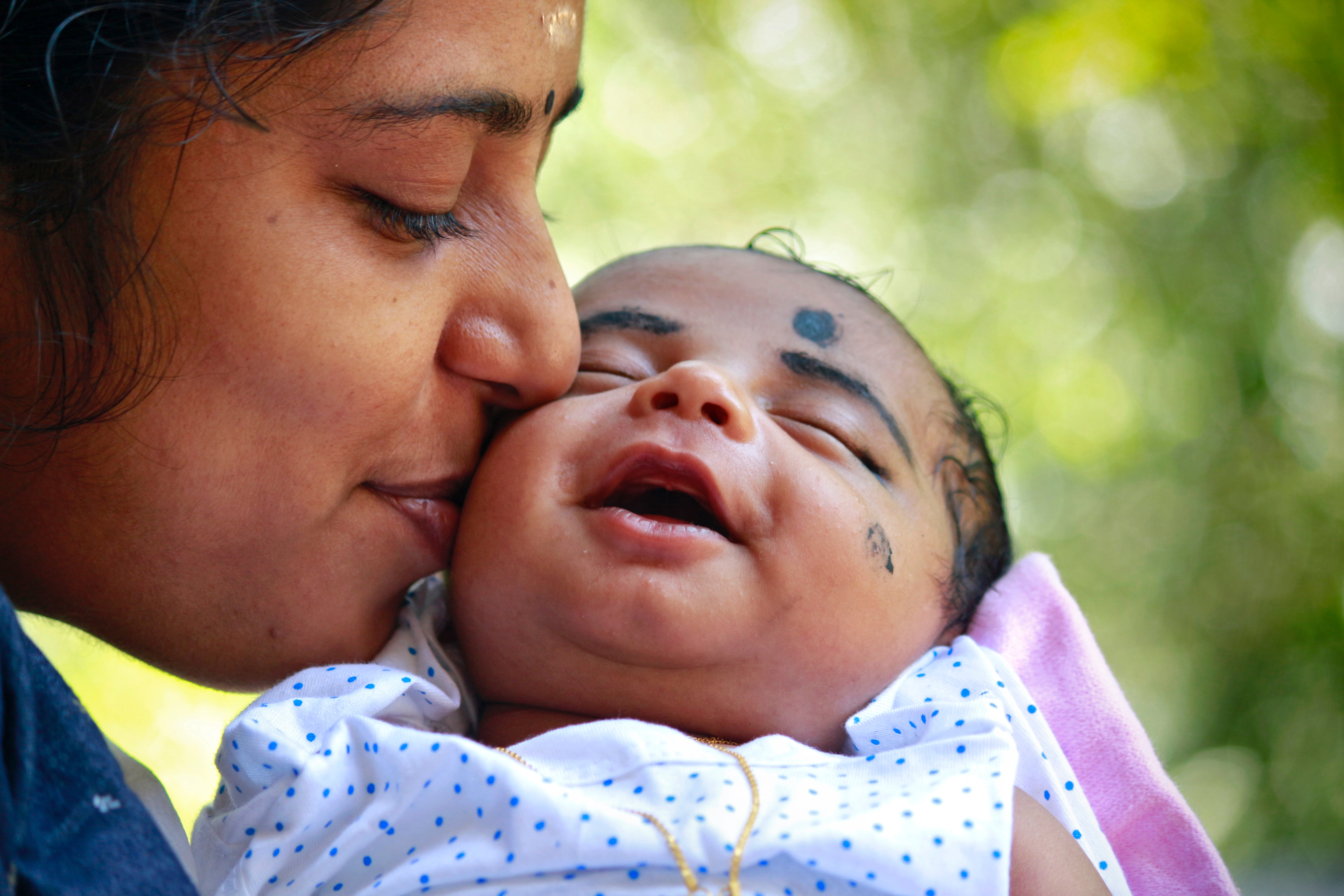 a mum kissing a little baby on the cheek