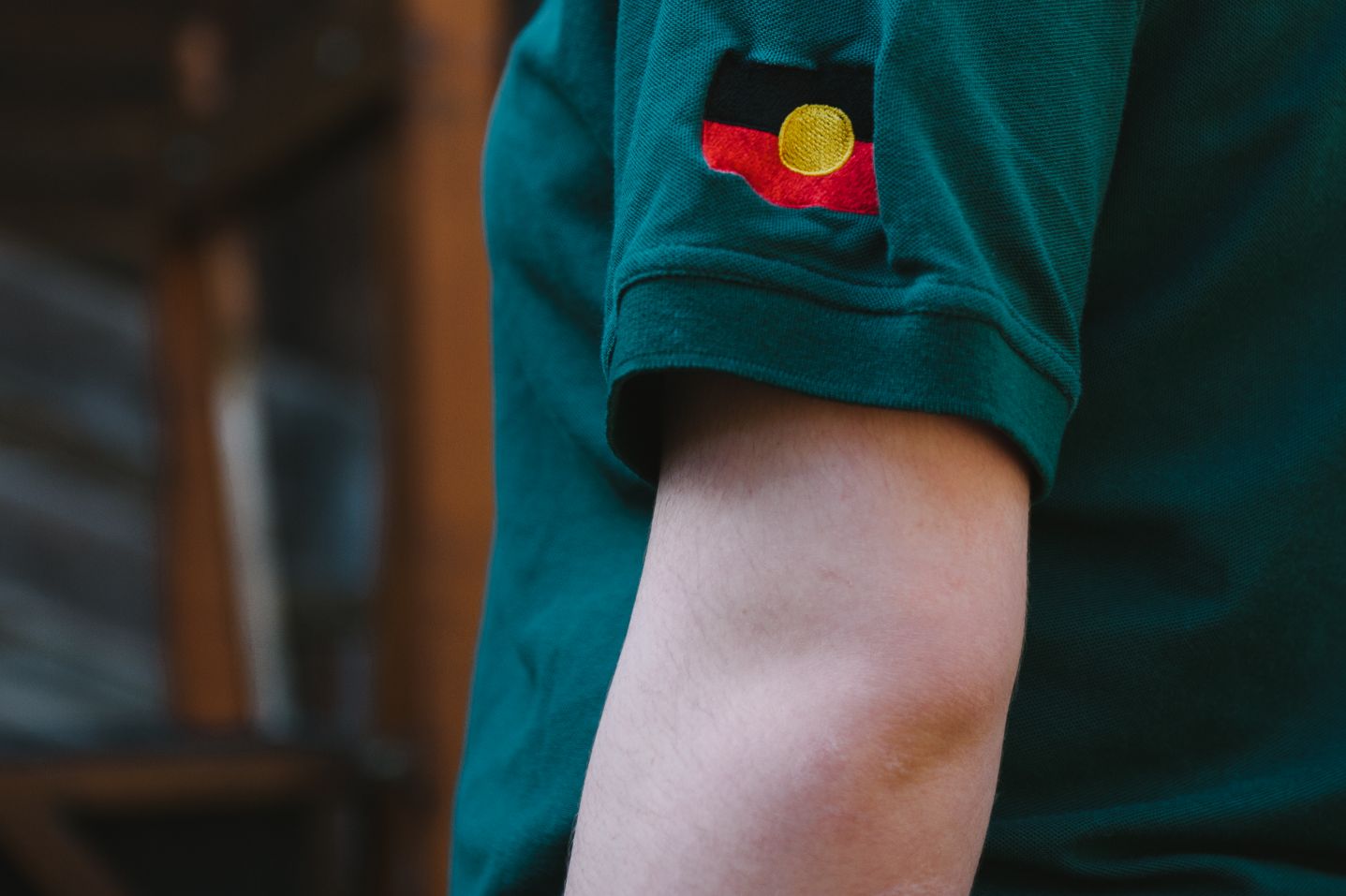 A picture of someone's arm with an aboriginal flag on the shirt 