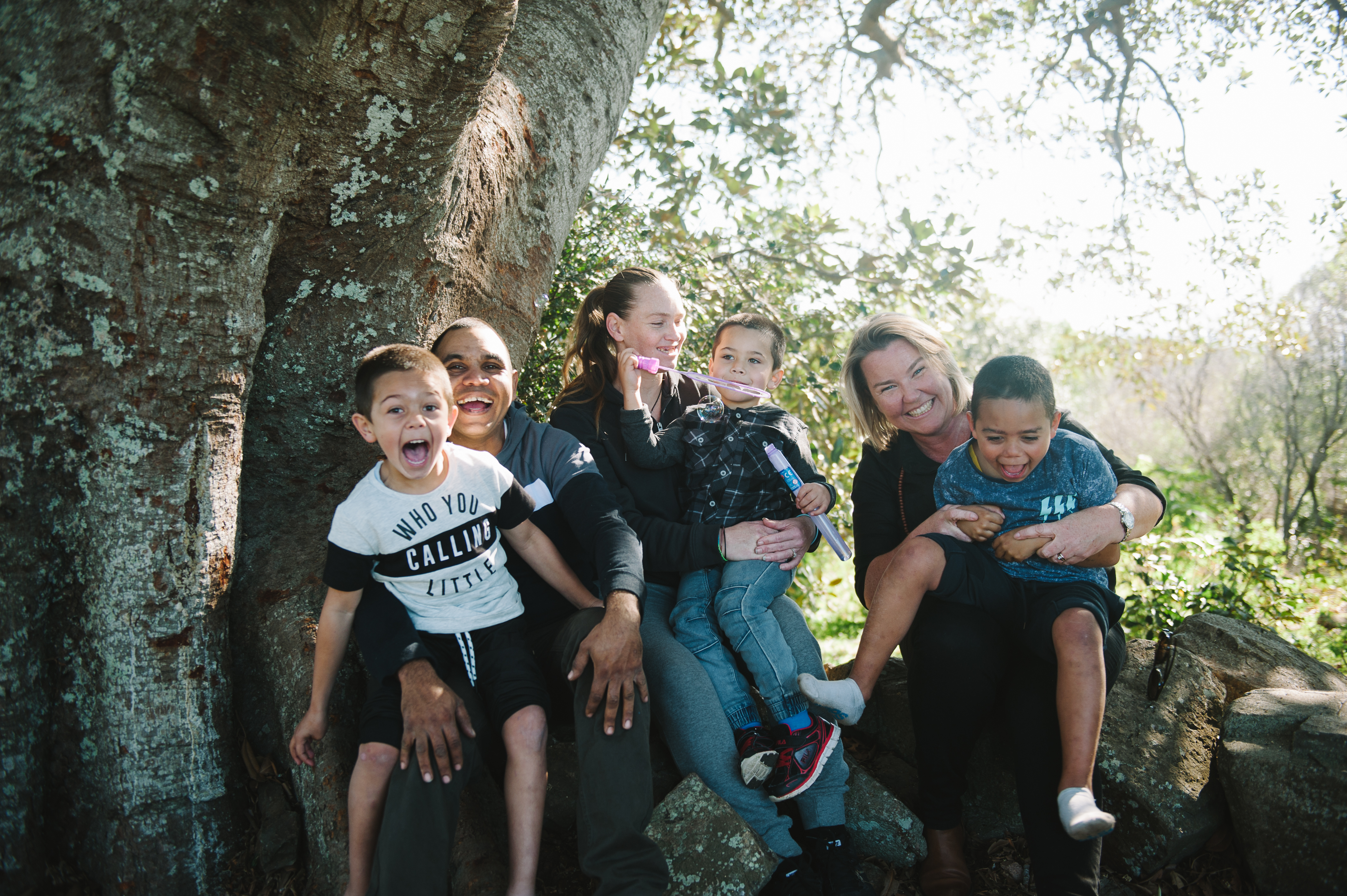 Three adult females with three children sitting on their laps all smiling and happy laughing 