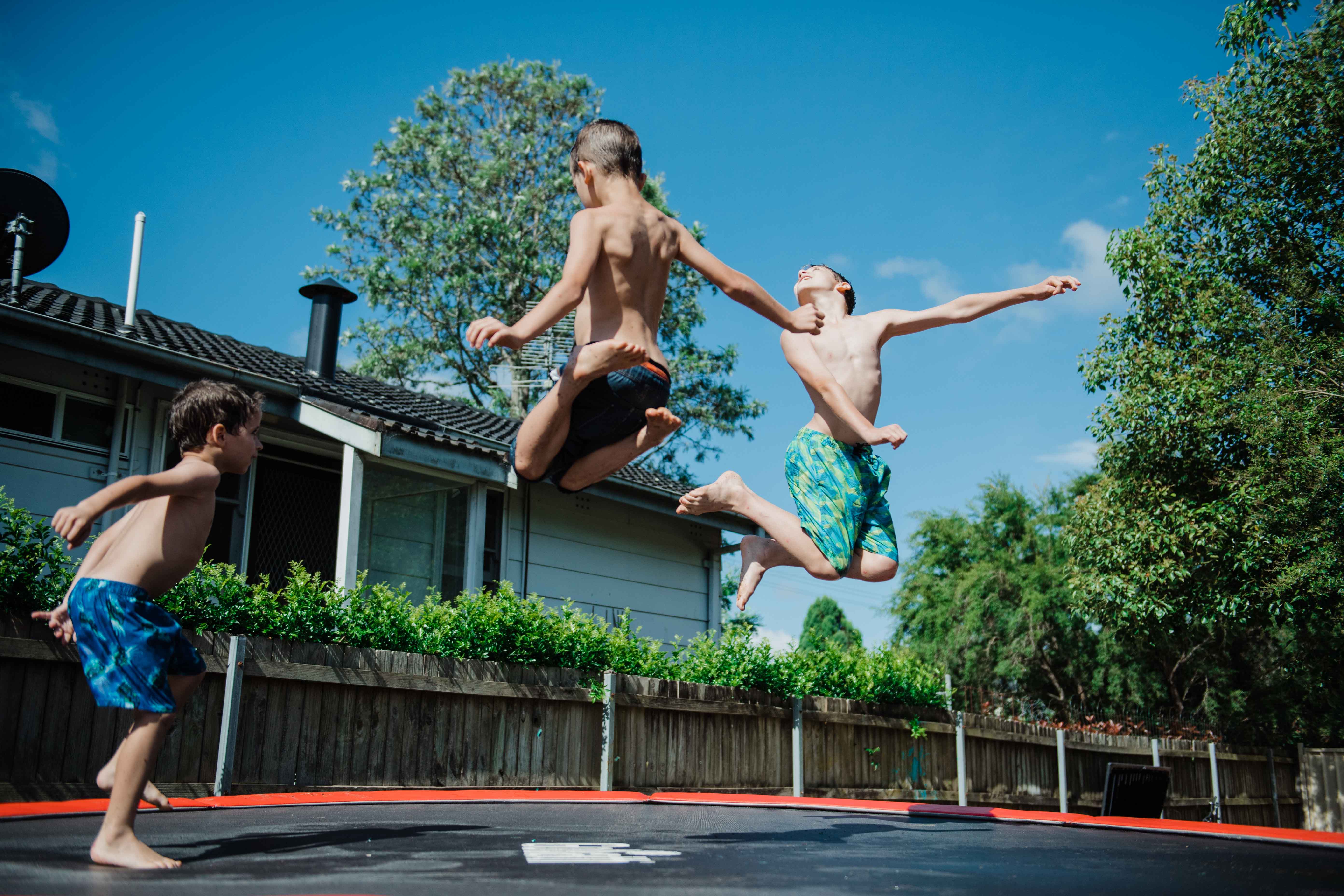 Three young boys jumping on a trampoline 