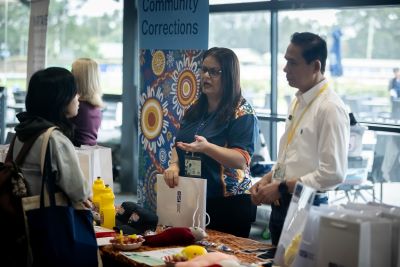 Two Corrective Service Staff behind stall  talking to an attendee