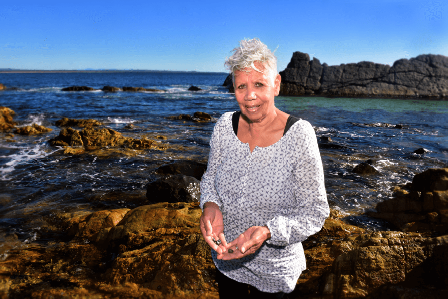 Lyn Davis indigenous elder educator standing on rocky beach