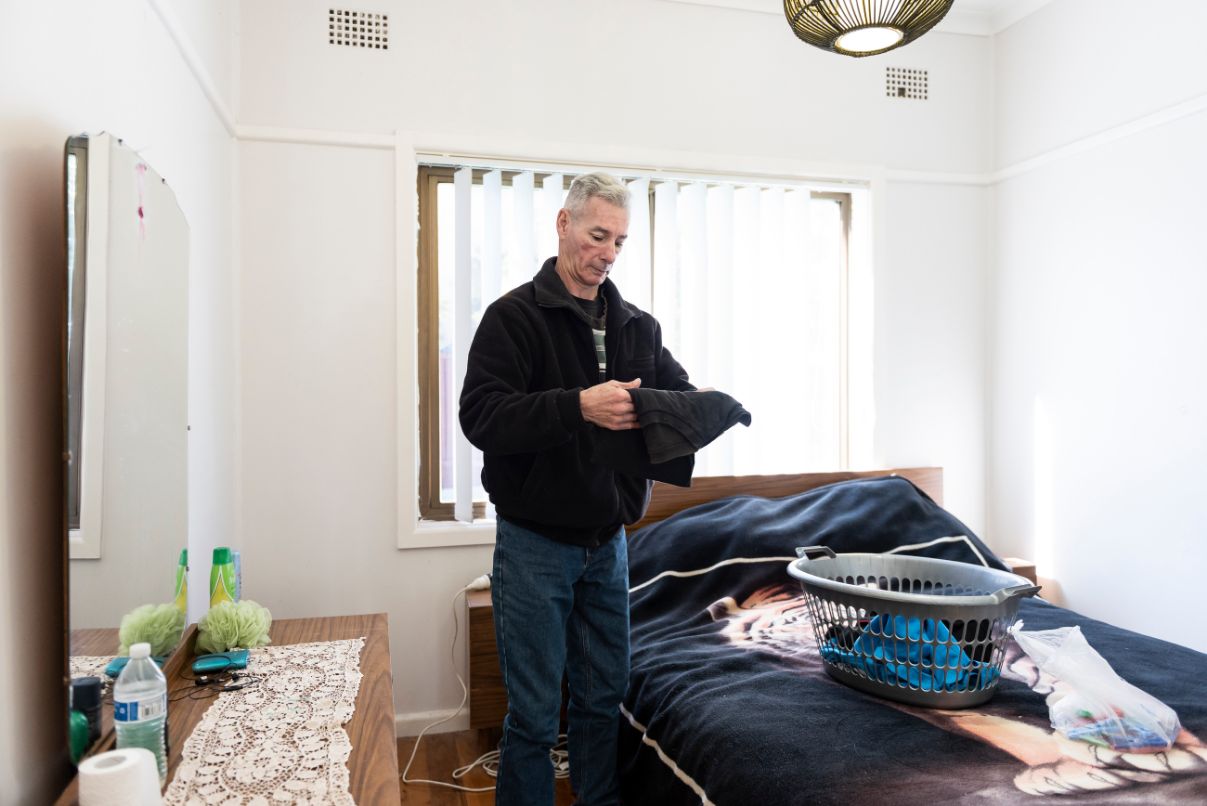 Garry pictured in his room folding his laundry on his bed. 