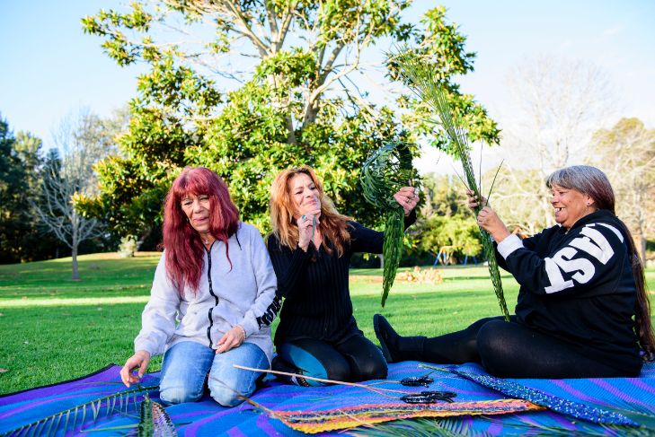 Tanya sitting in a park on a mat along with two other female friends.