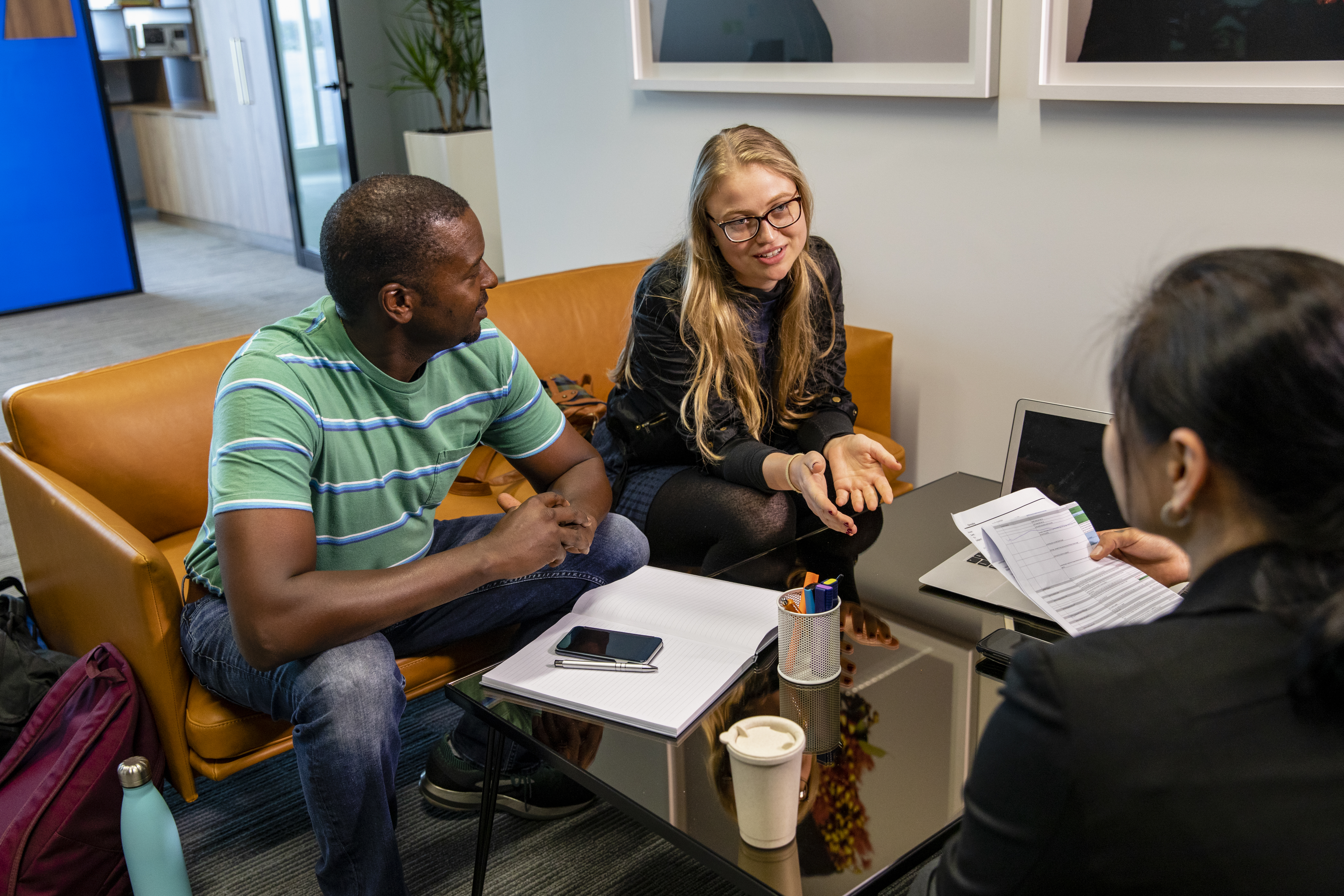 A group of community workers meeting meeting at a table with notebooks and coffee.